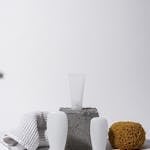 A clean and elegant spa setup with cosmetic bottles, sponge, and towel on a white background.