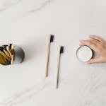 Flat lay of bamboo toothbrushes and eco-friendly dental powder emphasizing sustainable hygiene.