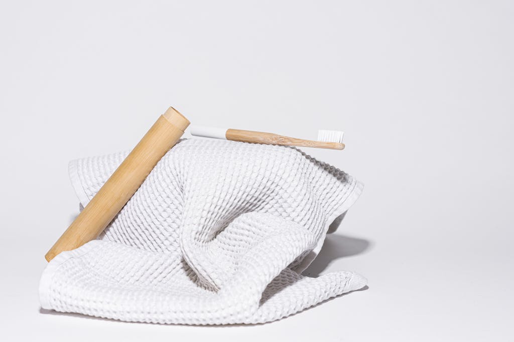 Minimalist photo of a bamboo toothbrush resting on a white towel, showcasing sustainable living.