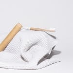 Minimalist photo of a bamboo toothbrush resting on a white towel, showcasing sustainable living.
