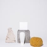 Minimalist setup featuring skincare items, sponge, and pouch on white background.