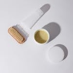 Top view of skincare products including a brush and cream on a white background with copyspace.