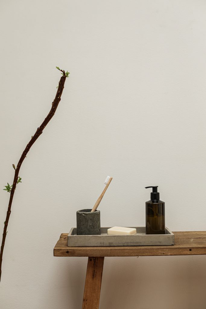 A simple arrangement of bathroom items including a wooden toothbrush and liquid soap dispenser.