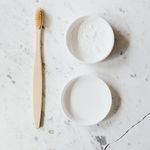 Top view layout of wooden toothbrush and tooth powder placed on chipped marble surface of table