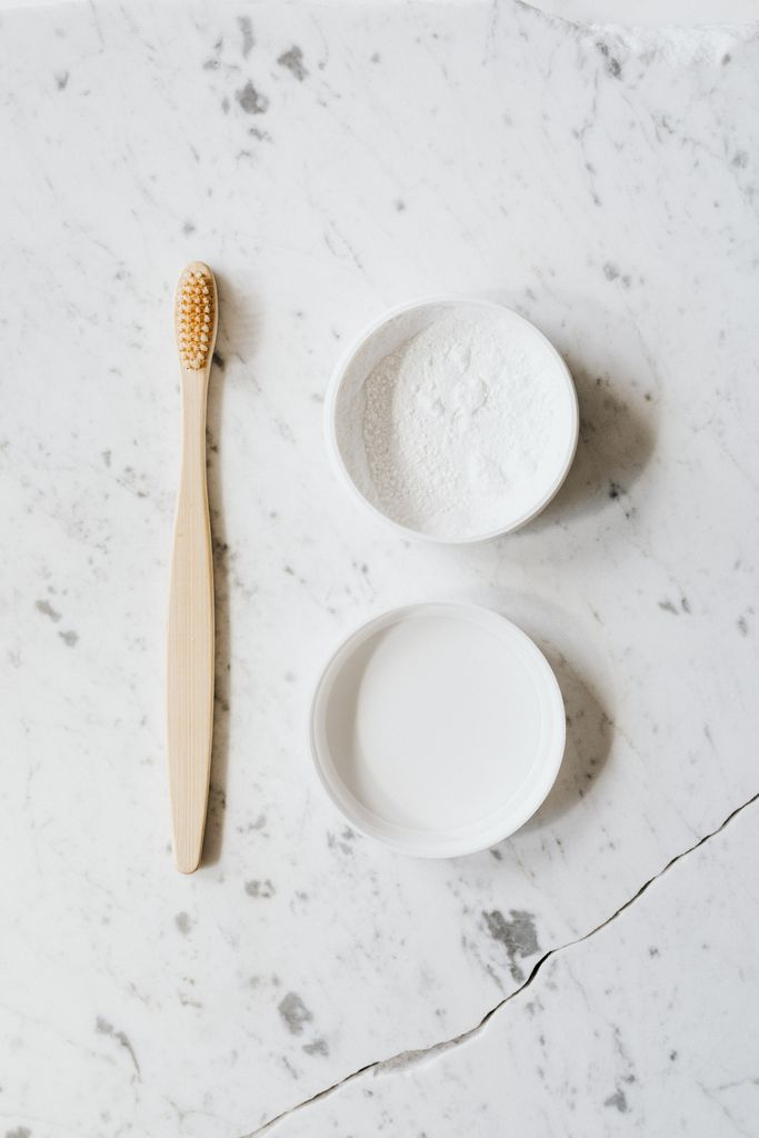 Top view layout of wooden toothbrush and tooth powder placed on chipped marble surface of table